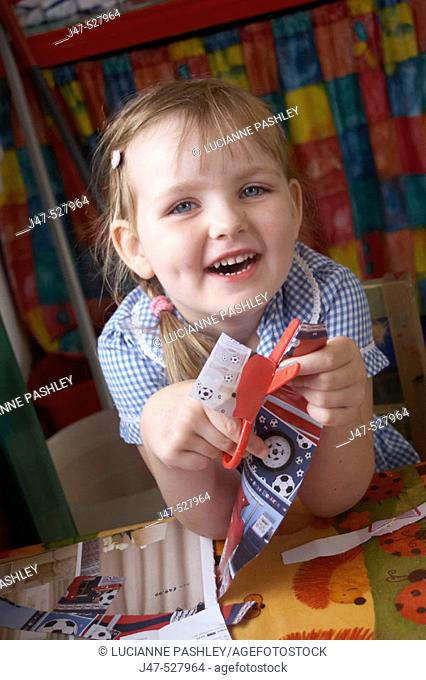 4 year old girl at nursery, smiling into camera, cutting