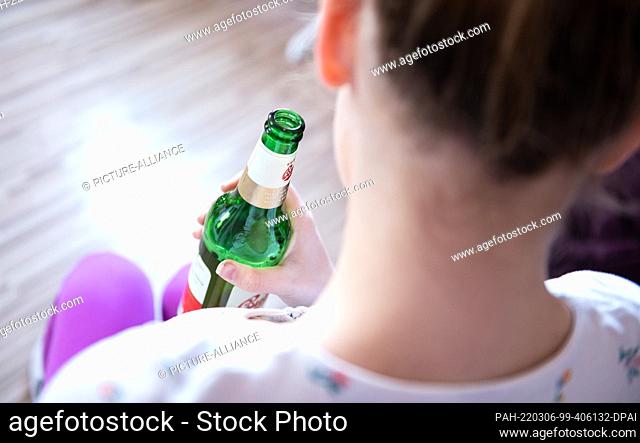 04 March 2022, Baden-Wuerttemberg, Rottweil: Illustration: A teenage girl holds a bottle of beer in her room. (To dpa ""DAK: Depressed kids abuse addictive...