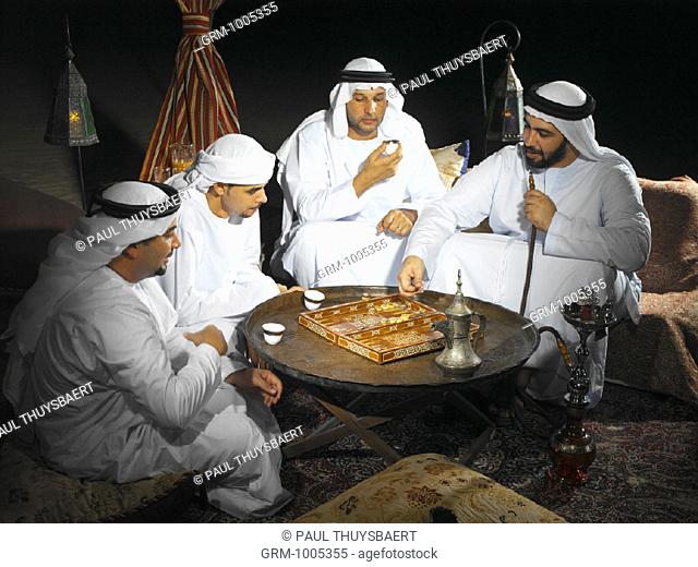 Arab men playing backgammon in Arabian tent