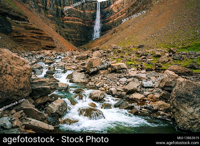 Hengifoss waterfall in East Iceland. Hengifoss is the third highest waterfall in Iceland and is surrounded by basaltic strata with red layers of clay between...