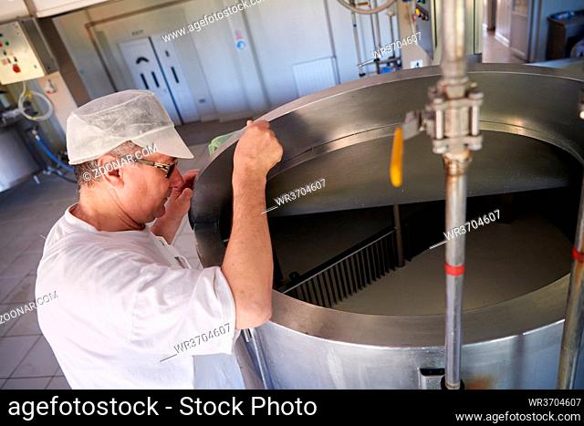 Cheese production male cheesemaker employee working in factory