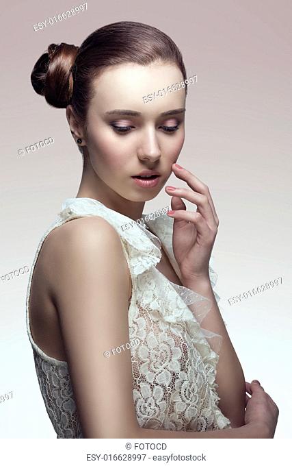 elegant fashion brunette woman posing with creative chignon hair-style and wearing sexy white lace shirt