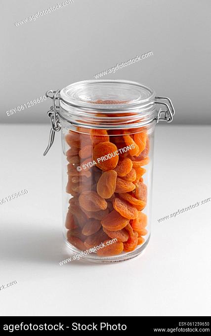 close up of jar with dried apricot on white table