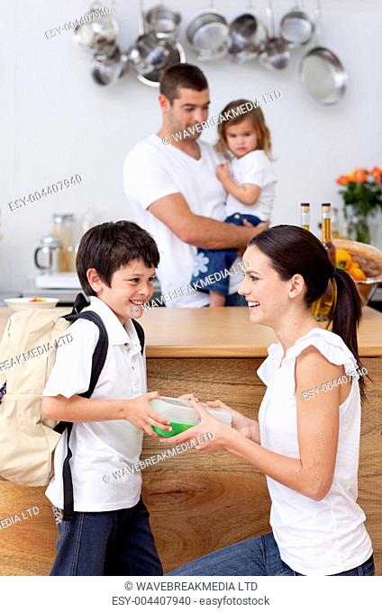 Smiling mother giving school lunch to her son