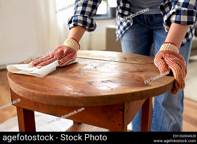 woman cleaning old table surface with paper tissue