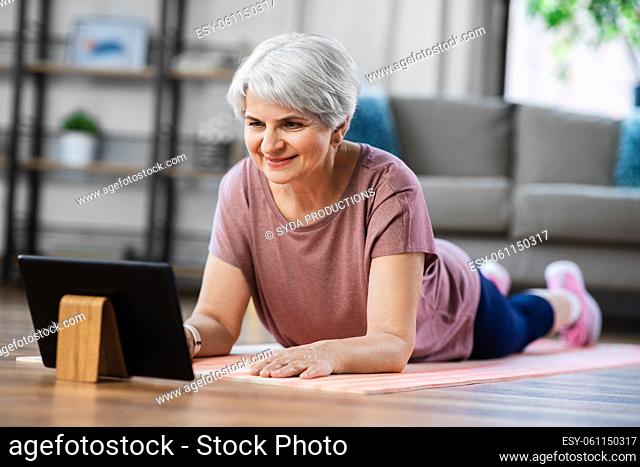 happy woman with tablet pc exercising at home