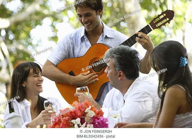 South American man playing guitar for friends