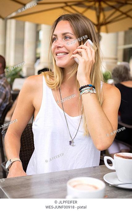 Young woman in a street cafe on cell phone looking around
