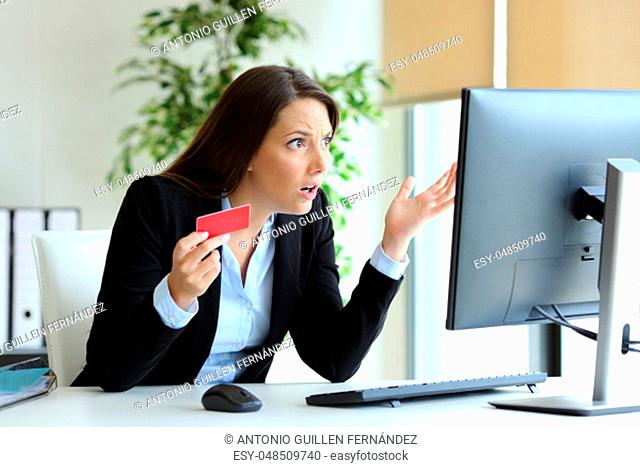 Confused office worker trying to pay online with credit card on a desktop computer