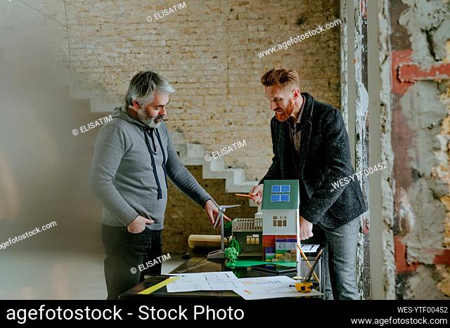 Customer having discussion with architect over model house at construction site