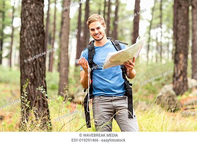 Young handsome hiker using map and compass