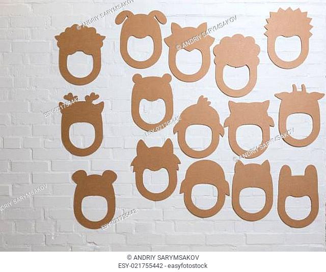 Set of cardboard masks on a white brick wall