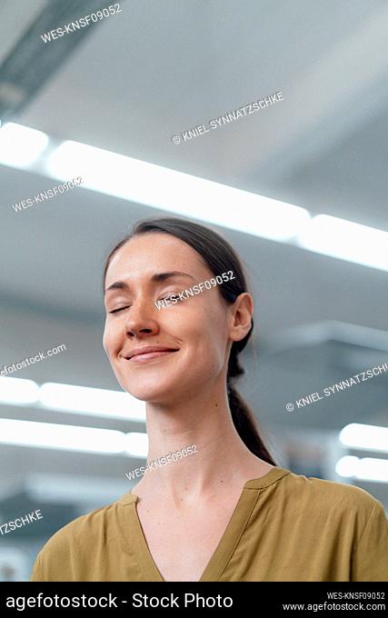 Smiling businesswoman with eyes closed in industry