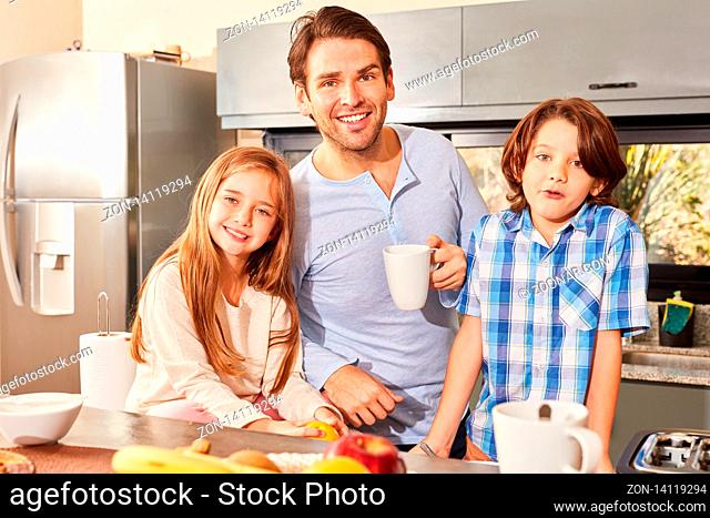 Alleinerziehender Vater und zwei Kinder beim Frühstück morgens in der Küche