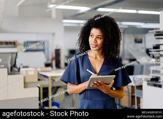 Afro female professional looking away while holding digital tablet in office
