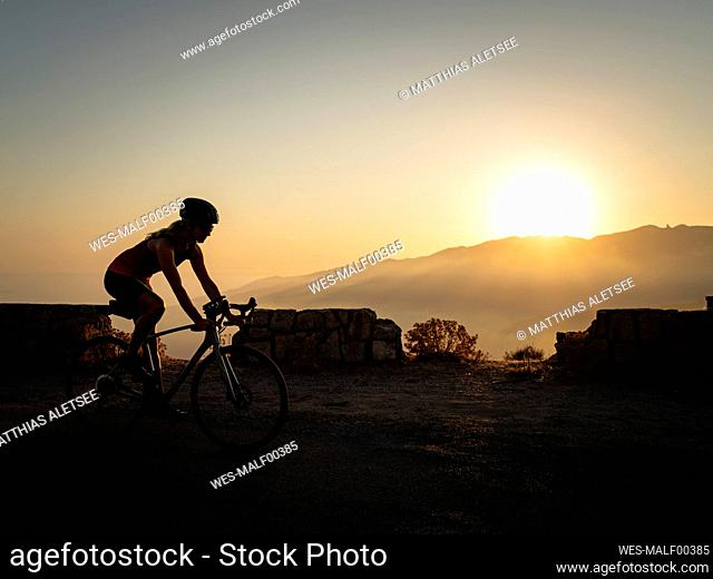 Sportswoman riding mountain bike at sunset