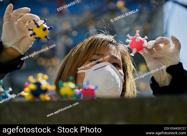 Asian woman with a protective mask and virus models on her hands. The concept of Coronavirus