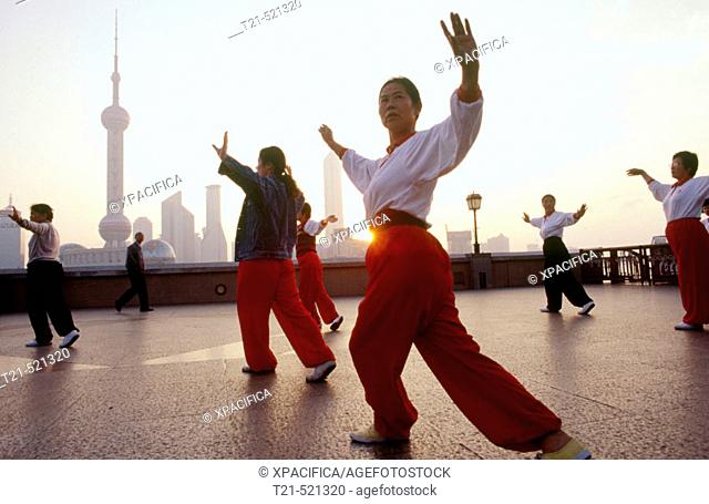 People dance on the 'Bund' or 'Wai Tan'. The waterfront of Shanghai. Across the river is the Pudong skyline. China