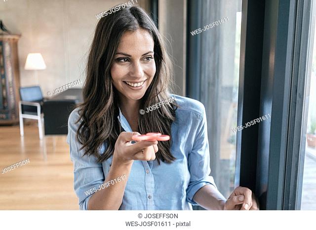 Smiling woman with fidget spinner at the window