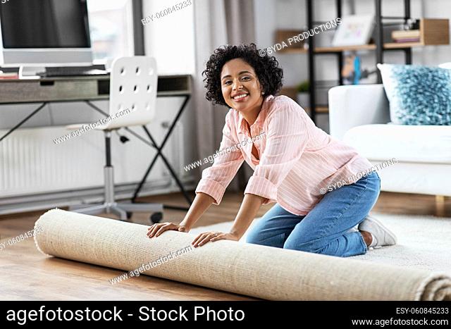 young woman unfolding carpet at home