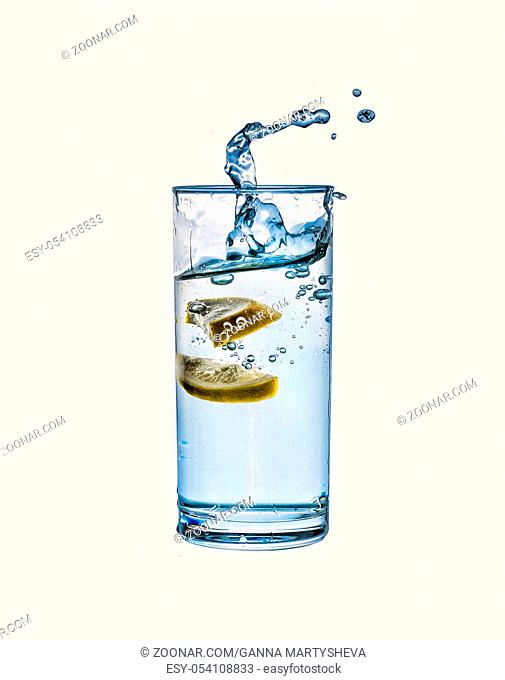 Water. Splash in a glass of pure water with a lemon isolated on a white background
