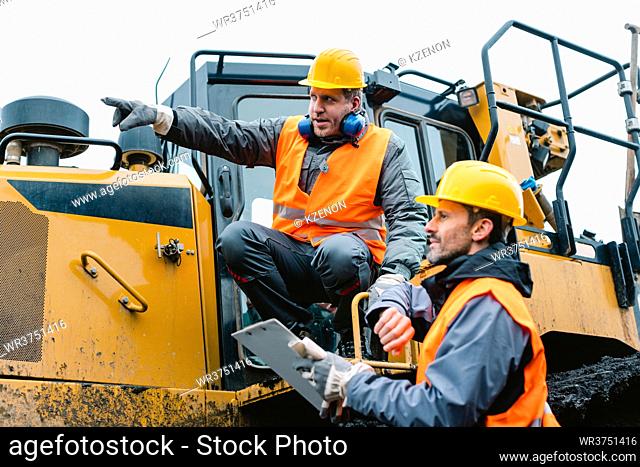 Worker sitting on heavy excavation machinery in mining operation