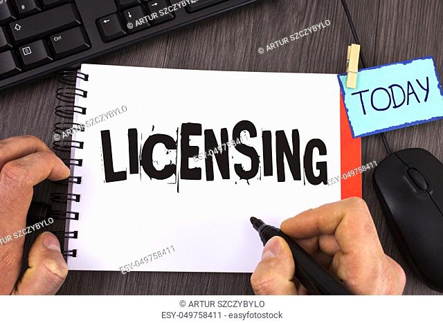 Handwriting text Licensing. Concept meaning Grant a license Legally permit the use of something Allow activity written by Man Notepad wooden background Marker...