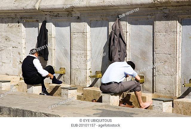 Sultanahmet. The New Mosque or Yeni Camii. Two men washing and making ablutions before prayer