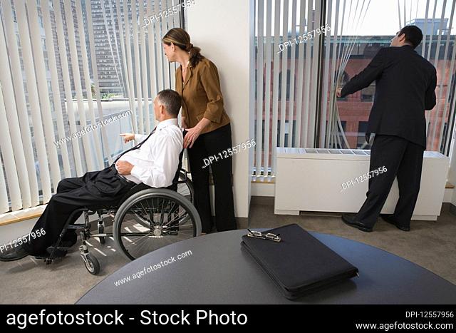 Three business executives looking through windows in an office