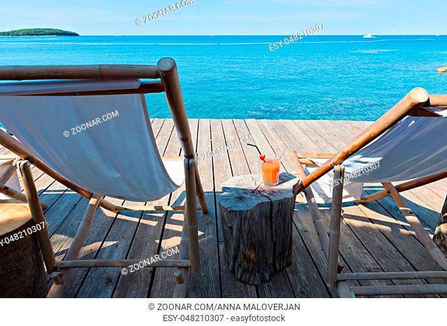 Wooden floor with chaise-longues and bue sea in Istria, Croatian coast