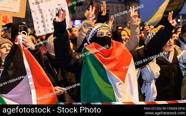 02 December 2023, Hamburg: Participants in a pro-Palestinian demonstration make the Victory sign while standing at a barrier