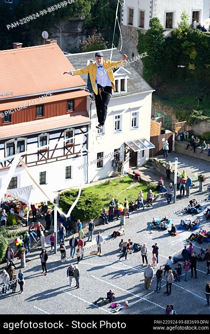 24 September 2022, Saxony, Hohenstein: The slackline runner Ruben Langer runs on a rope between the castle and the town church across the market square at the...