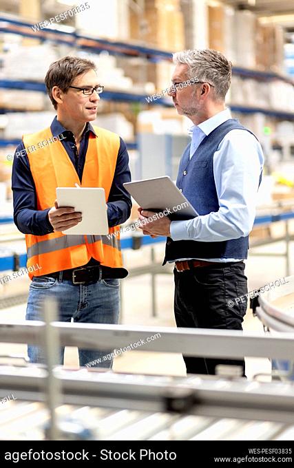 Worker with tablet PC discussing with manager in warehouse