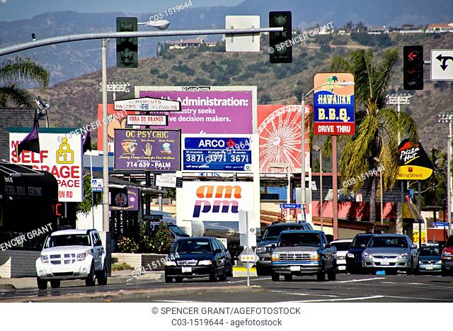 Afternoon traffic passes retail advertising signs in Orange, CA