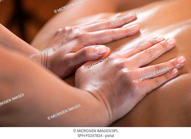 Close up image of physiotherapist massaging female patient with injured back muscle. Sports injury treatment