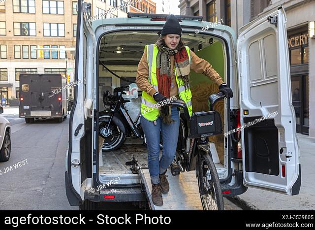 Detroit, Michigan - A worker unloads an electric bike from a van near a docking station of Detroit's MoGo bike share system
