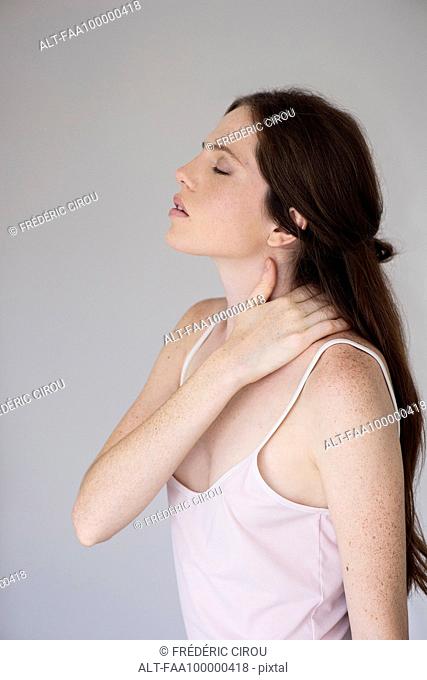 Woman massaging neck, side view