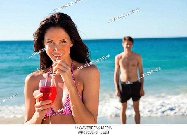 portrait of a woman holding a cocktail on the beach