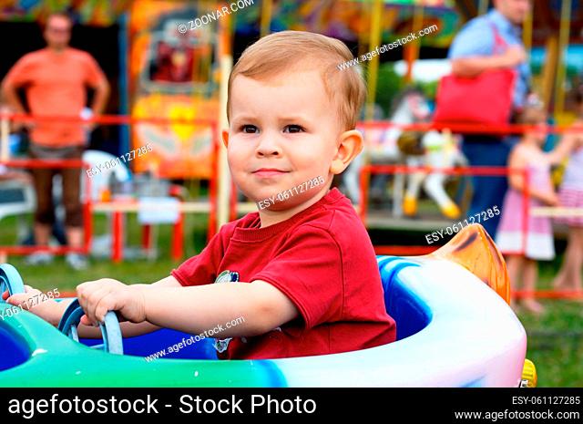 Two years old child driving toy vehicle in the amusement park