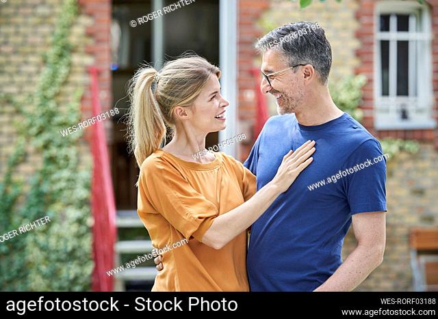 Happy couple looking at each other in front of house