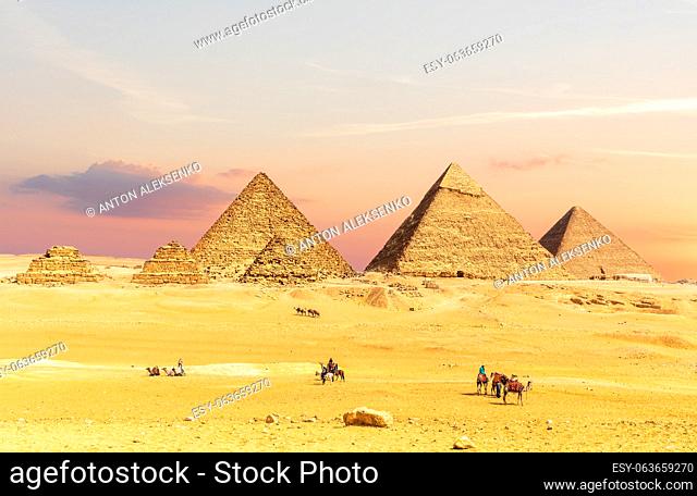 Pyramids of Egypt at sunset with tourists nearby, Giza desert, Cairo