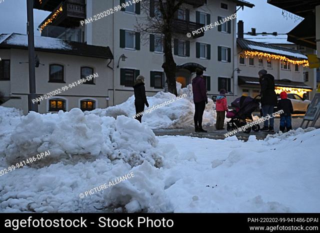 02 February 2022, Bavaria, Ruhpolding: Pedestrians stand on the sidewalk between snow mountains in the center of the village. Photo: Uwe Lein/dpa