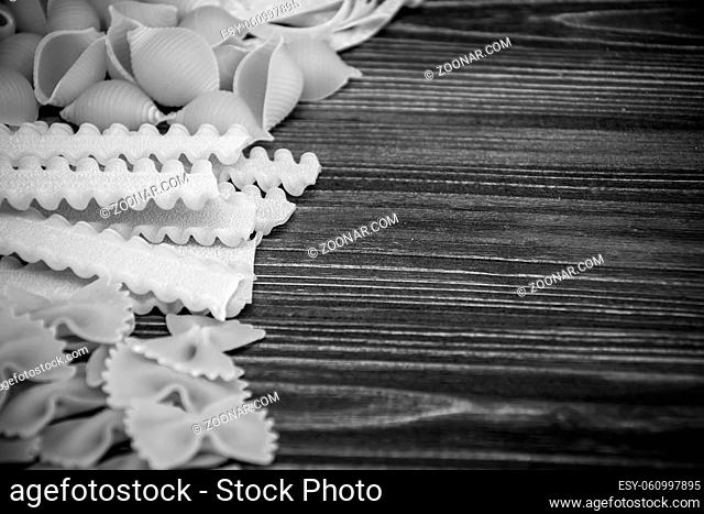 Pasta mix on dark wooden table background. Black and white