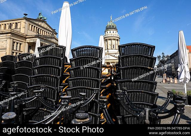 16 March 2020, Berlin: Stacked chairs from a street café can be seen on the Gendarmenmarkt in front of the Schauspielhaus (l) and the French Cathedral