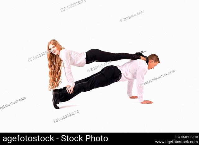 Side view of male manager in formal wear lifting cheerful female colleague against white background