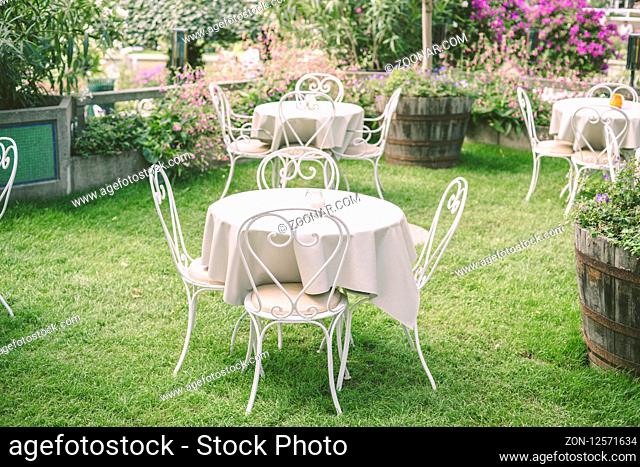 Romantic garden setting with vintage furniture and table cloth surrounded by flowers