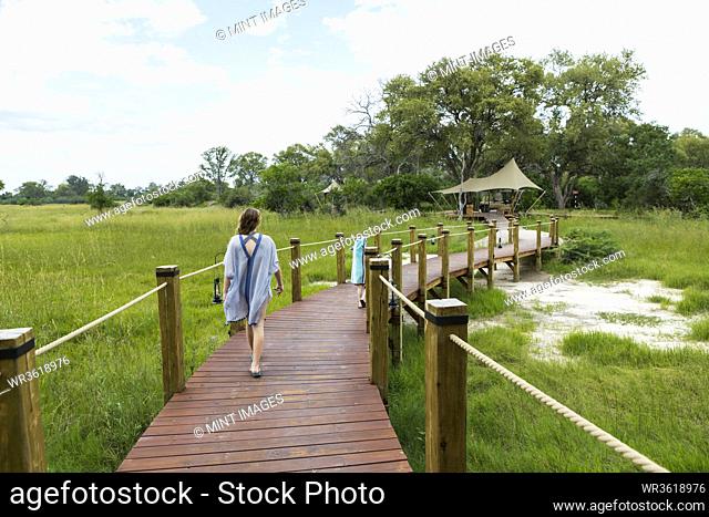 13 year old girl walking on wooden path, tented camp, Botswana