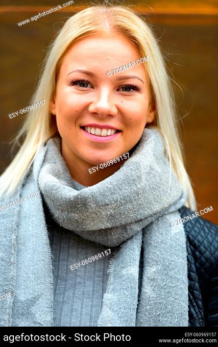 Portrait of young beautiful blonde Scandinavian woman against rusty old metal wall outdoors