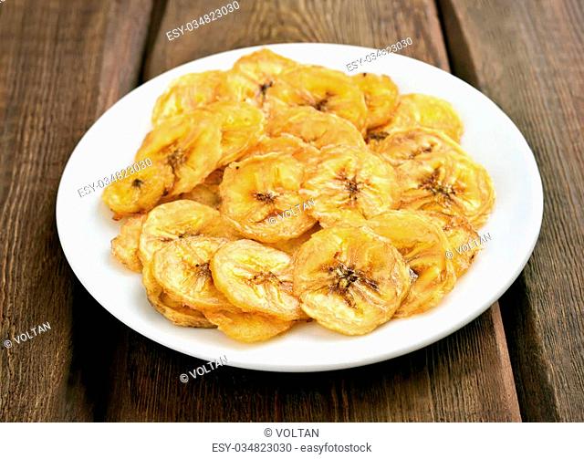 Banana chips on white plate, close up view