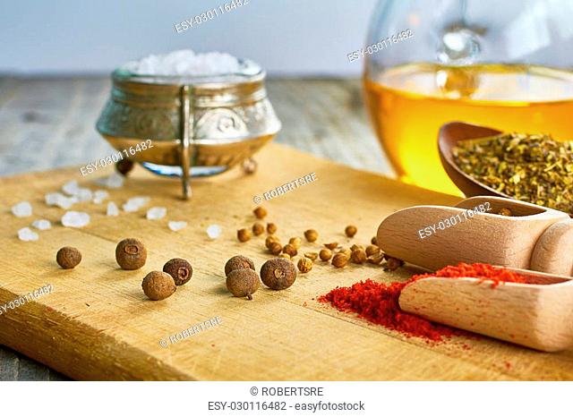 Various spices, salt, coriander seeds, chilly, herbs, allspice, olive oil, on wooden board